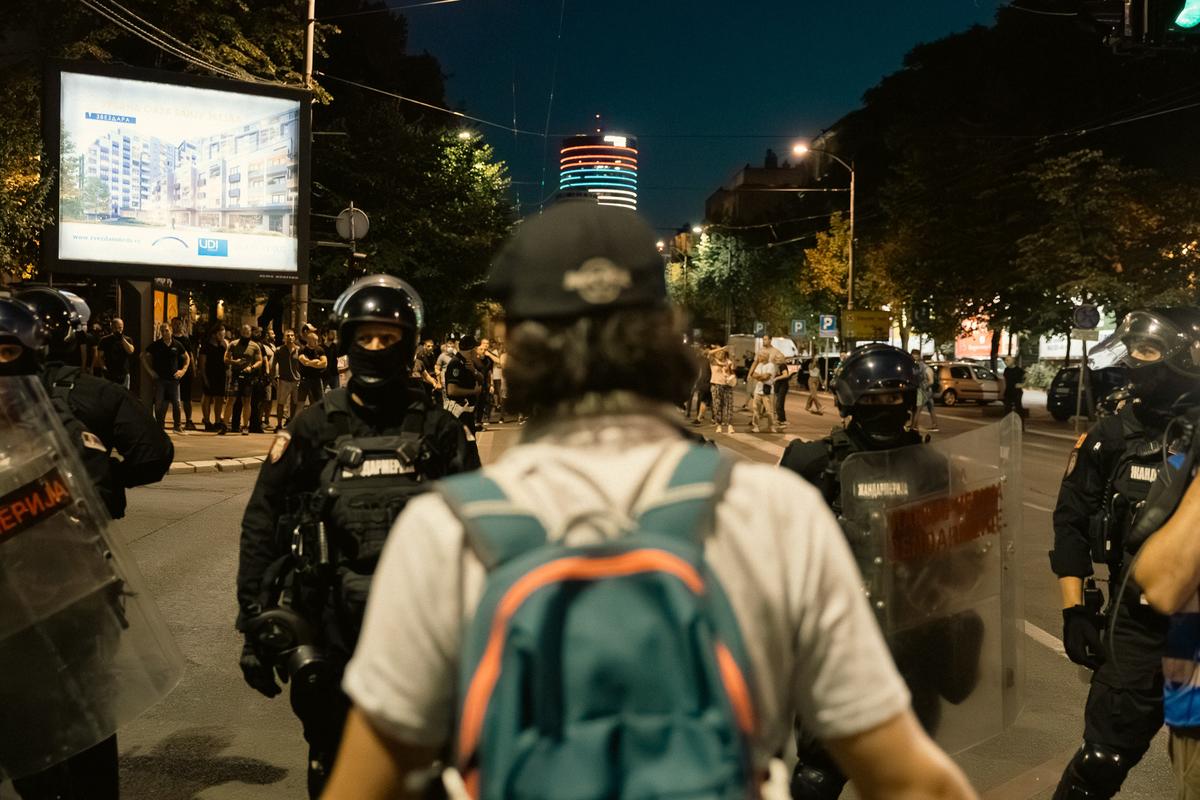 Demonstrant sa rancem hoda prema policijskom kordonu noću